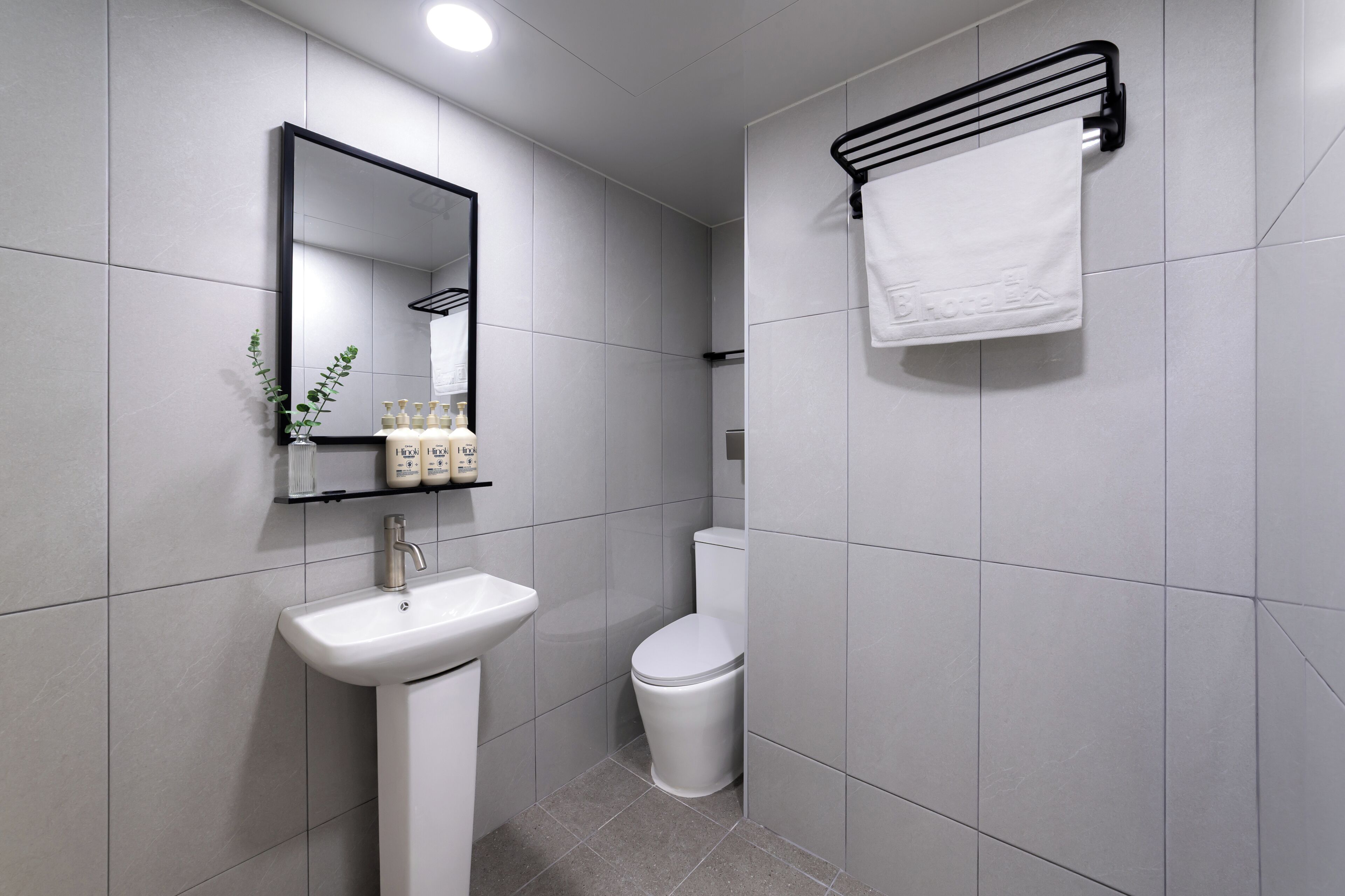 A modern bathroom with a white sink, toilet, and towel rack.