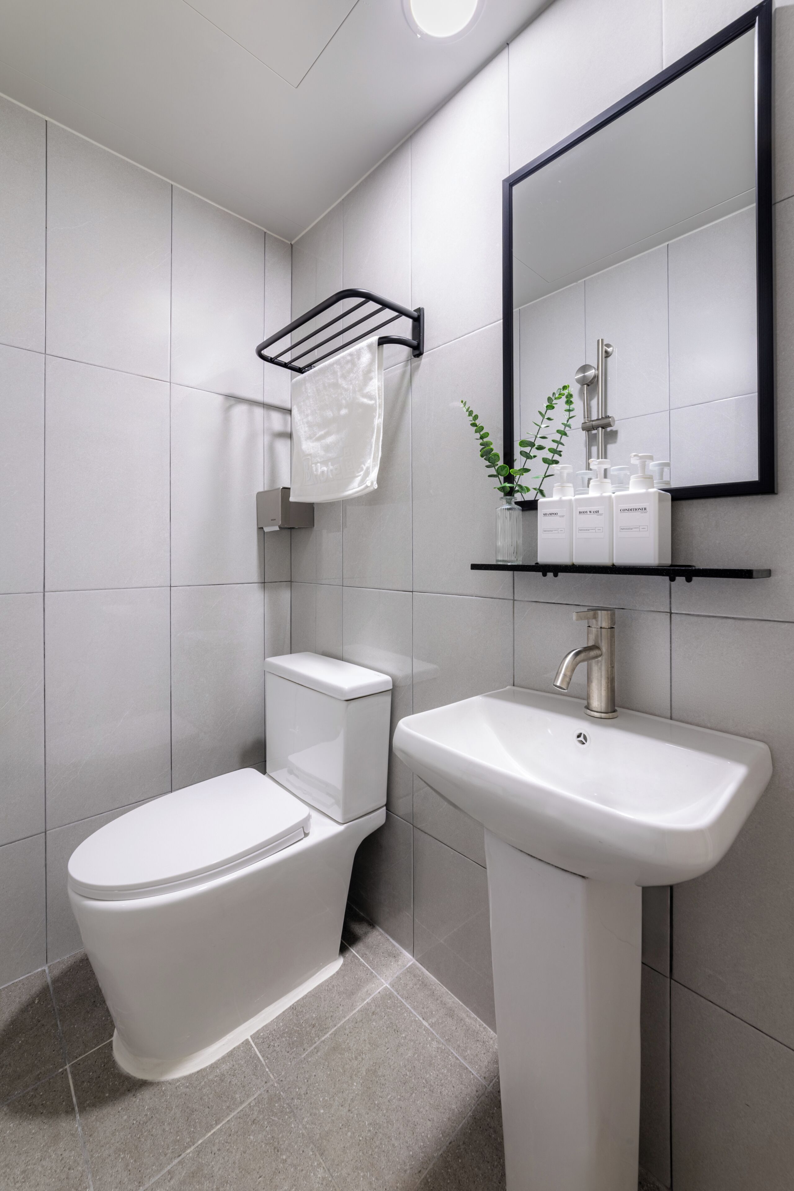 A modern bathroom with a toilet, sink, and mirror.