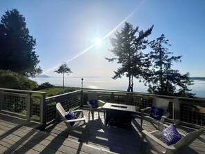 Une terrasse avec des chaises et une table, donnant sur une étendue d’eau et des arbres.