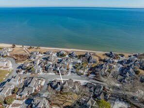 An aerial view of a coastal residential area with houses, a beach, and a clear view of the ocean. - Blue Tide Retreat Steps from Private Beach (Mashpee)
