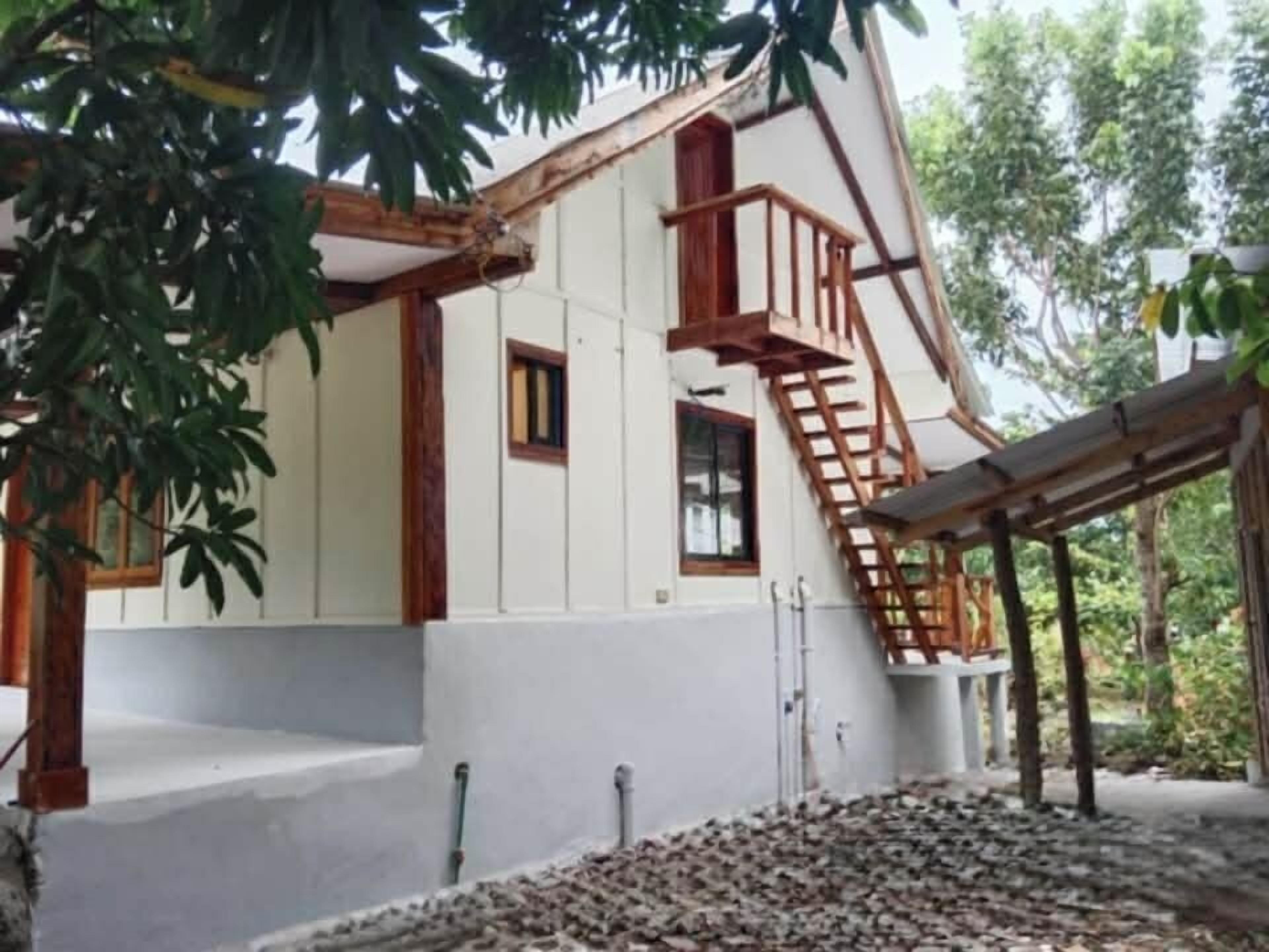 A building with a white exterior, wooden beams, and a wooden staircase leading to a balcony.