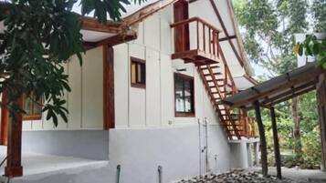 A building with a white exterior, wooden beams, and a wooden staircase leading to a balcony.