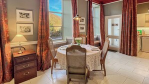Un coin repas avec une table ronde, des chaises, une lampe et des rideaux.