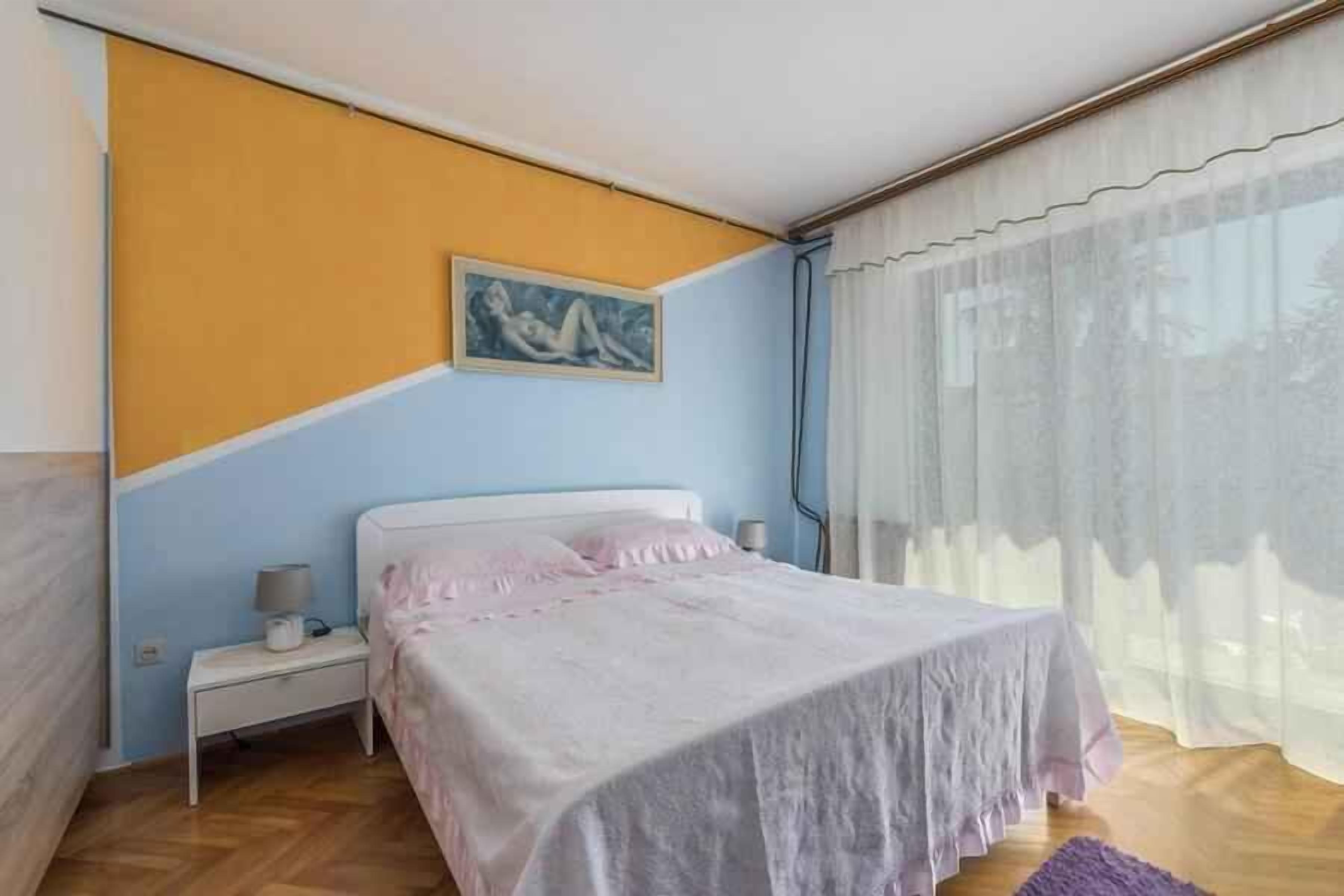 Une chambre à coucher avec un lit, une table de chevet et un tableau accroché au mur.