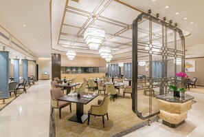 A hotel lobby with a central reception desk, multiple dining tables, chairs, and a chandelier. - Jeurong Hotel Shanghai (Shanghai)
