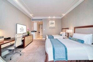 Hotelkamer met twee bedden, een bureau, een stoel, een televisie en een badkamer zichtbaar door een geopende deur.