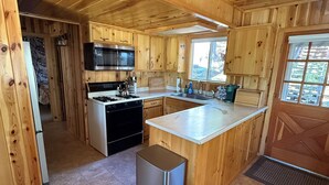 Ein Interieur einer Holzhütte mit einer Küche, die einen Herd, ein Spülbecken und Schränke beinhaltet.