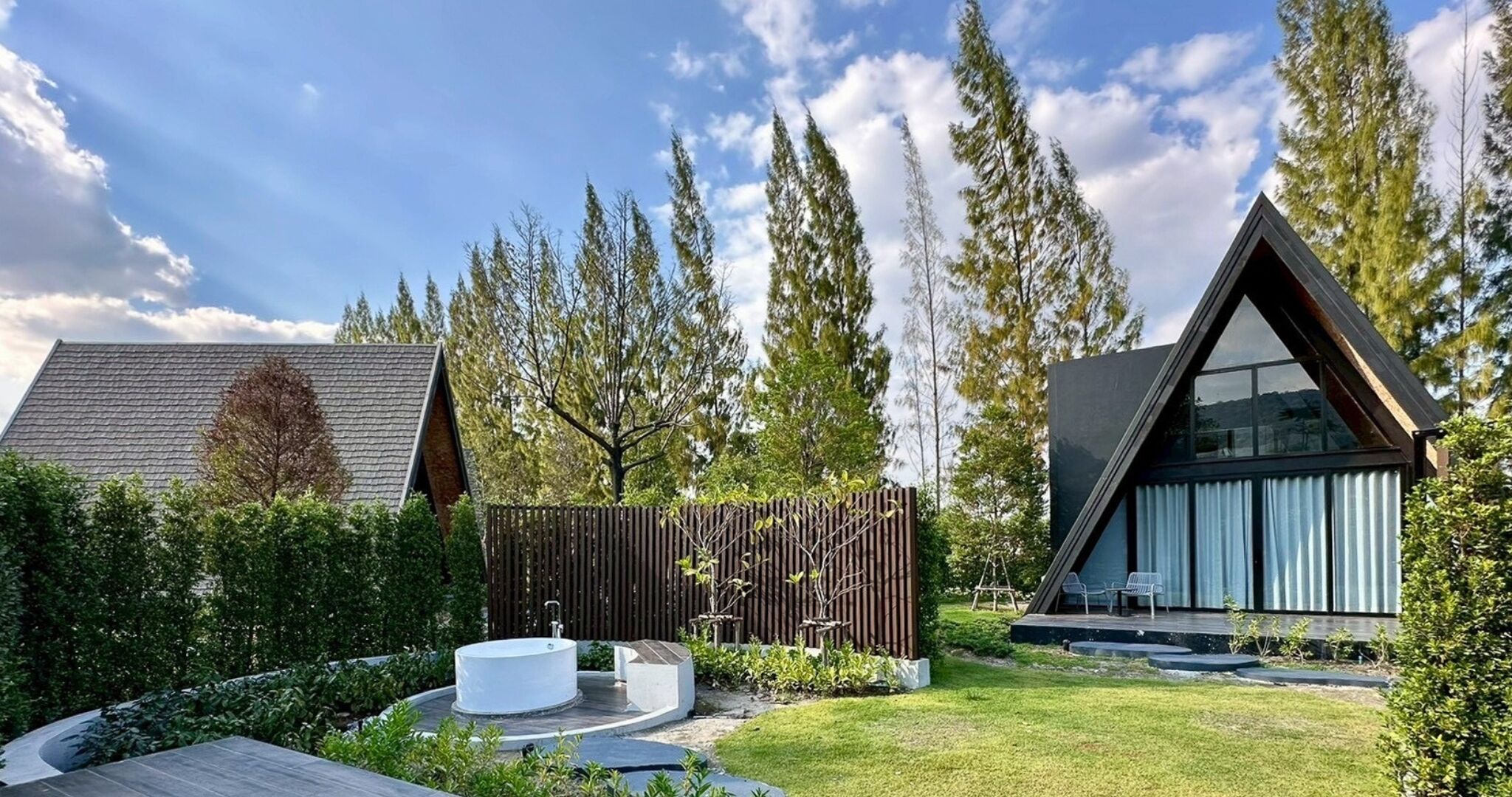 A modern house with a triangular roof, a swimming pool, and a wooden fence.