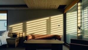 A modern hotel room with a bed, a desk, a sofa, and a large window allowing natural light. - Gion Kuromatsu (Kyoto)