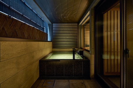 A modern bathroom with a stone sink, a bathtub, and a sliding glass door.