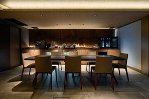 A modern kitchen with a dining area, wooden cabinets, a large table, and a television. - Gion Kuromatsu (Kyoto)