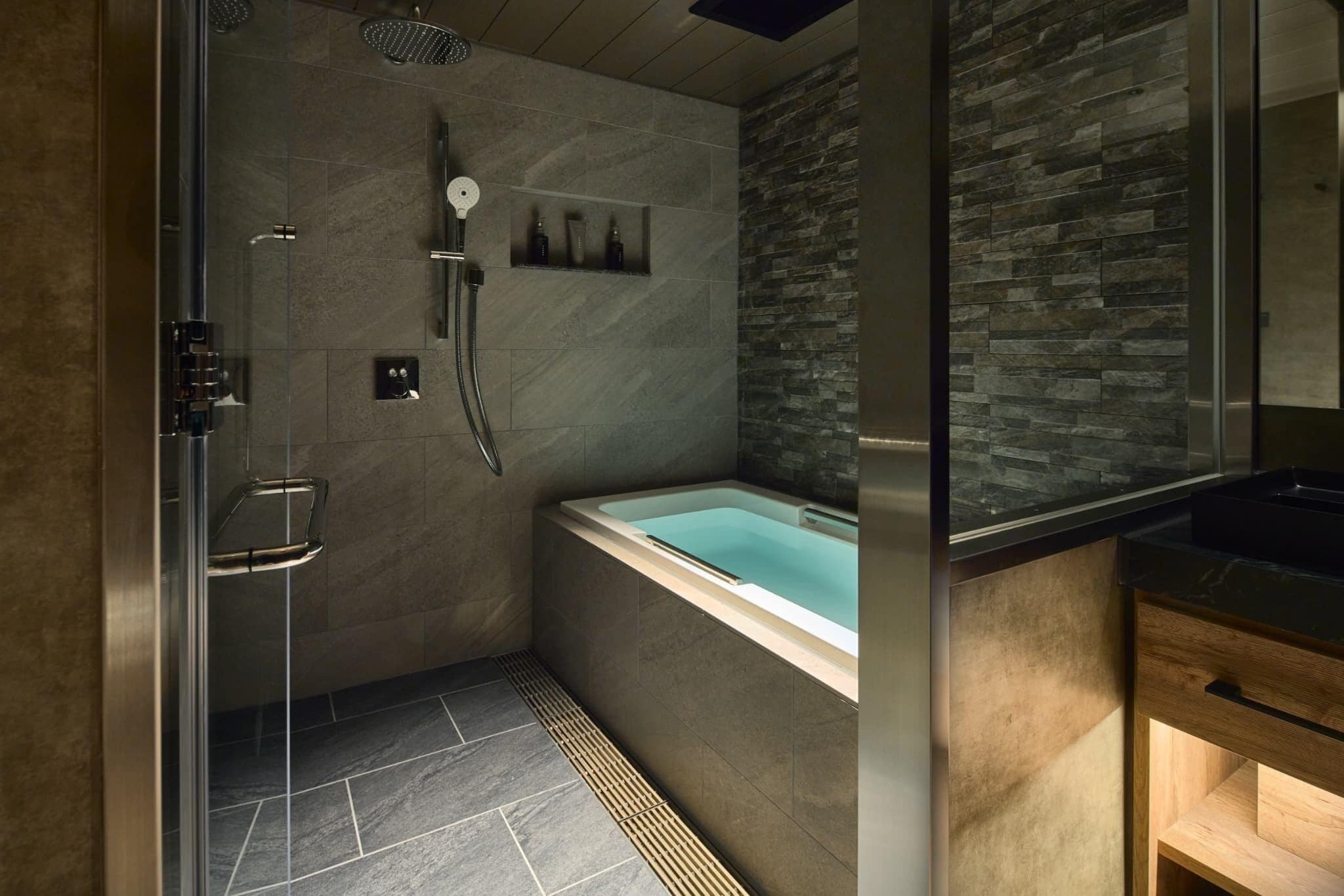 A modern bathroom with a glass-enclosed shower, a freestanding bathtub, and a wooden vanity.