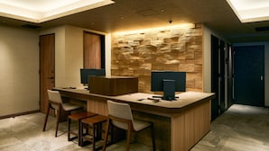 A modern hotel lobby with a reception desk, two chairs, and a stone wall. - Gion Kuromatsu (Kyoto)