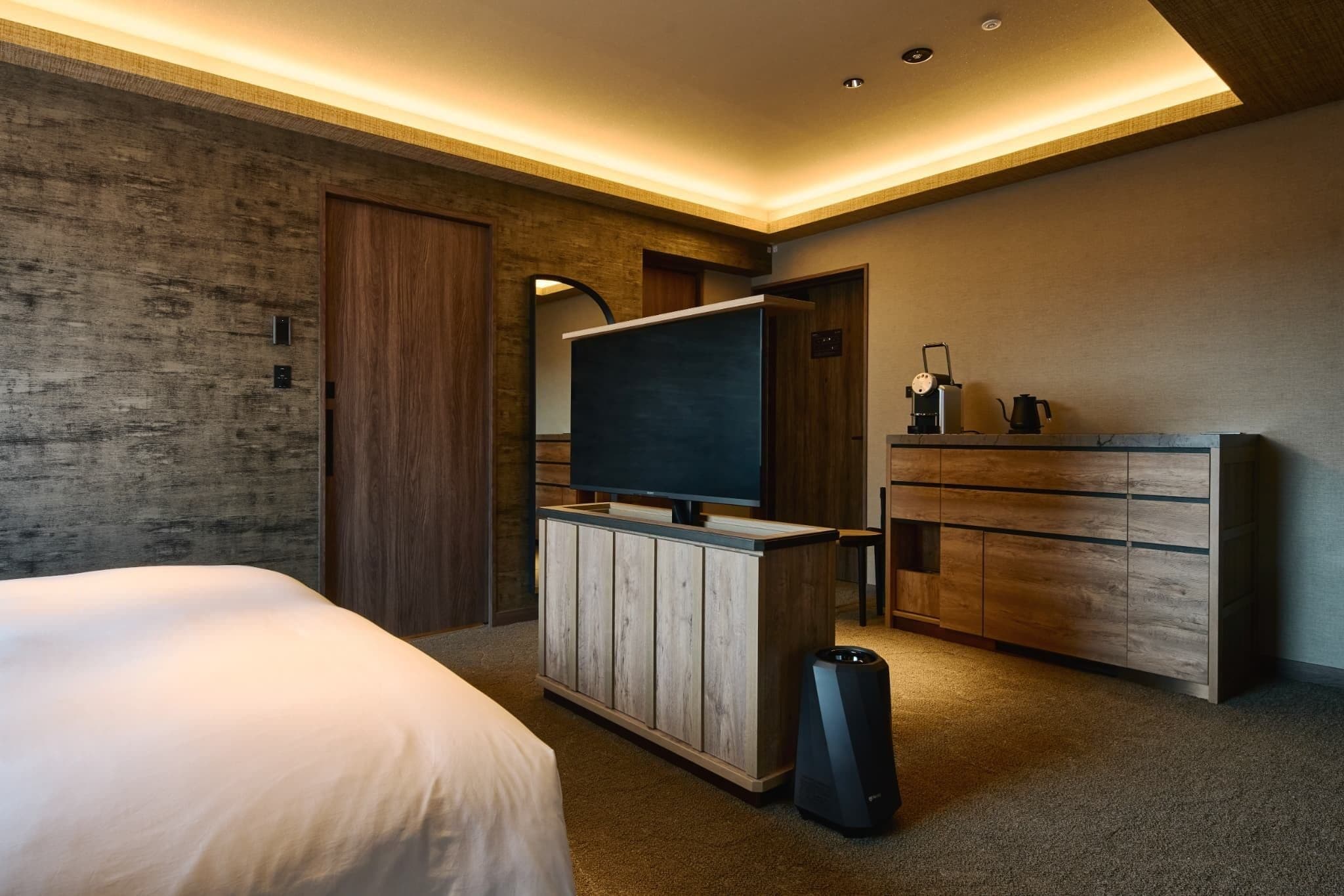 Une chambre d’hôtel moderne équipée d’un grand lit, d’une télévision, d’une commode en bois et d’un haut-parleur.