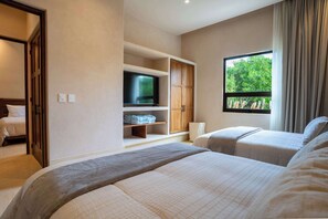 Une chambre d’hôtel avec un grand lit, une télévision, une armoire et une fenêtre donnant sur des arbres.