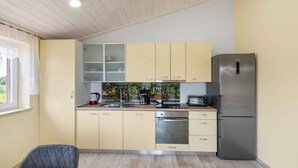 A compact kitchen with a refrigerator, oven, and a coffee maker. - Holiday apartment mit Klimaanlage und Pool (Umag)