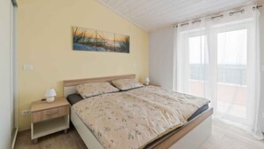 A bedroom with a bed, nightstands, a painting, and a balcony view. - Holiday apartment mit Klimaanlage und Pool (Umag)