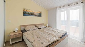 A bedroom with a bed, nightstands, a painting, and a balcony view. - Holiday apartment mit Klimaanlage und Pool (Umag)