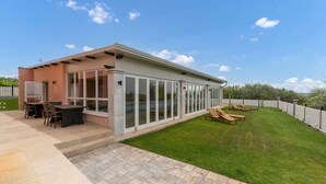 A modern house with a patio, a barbecue area, and a glass-enclosed room. - Holiday apartment mit Klimaanlage und Pool (Umag)