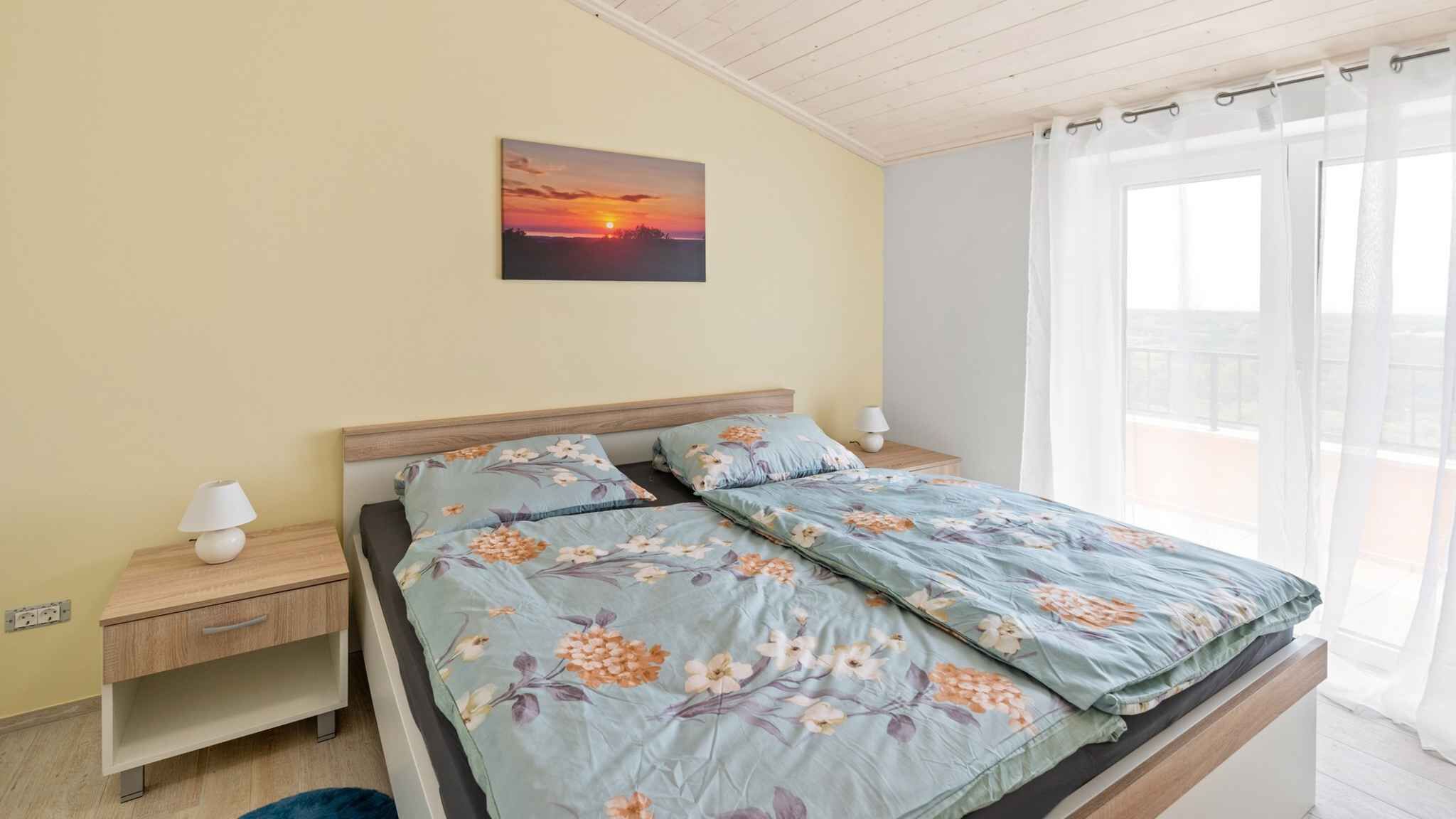 Une chambre à coucher avec un lit, des tables de chevet, une lampe, un tableau et une fenêtre avec des rideaux.
