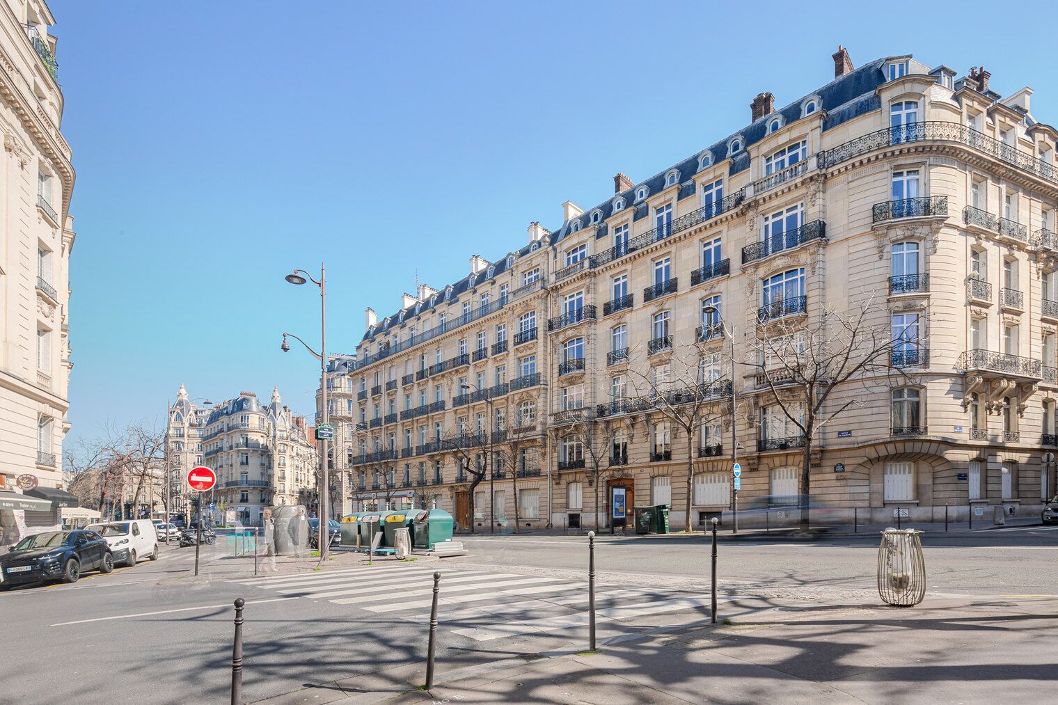 A multi-story building with classical architecture, a street view, and a clear sky.