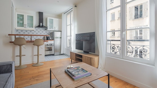 Een modern appartement met keuken, eethoek en televisie.