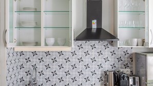 Een keuken met een modern design, met een roestvrijstalen afzuigkap, een inbouwoven, een koffiezetapparaat en een broodrooster.