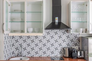 A kitchen with a modern design, featuring a stainless steel range hood, a built-in oven, a coffee maker, and a toaster. - Blueground | Plaine-Monceau, view, nr Parc Monceau (Paris)