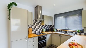 Una cocina moderna con una isla central, horno empotrado y una ventana con persianas.