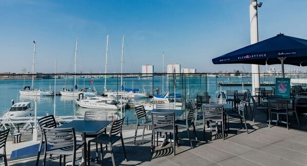 Un port de plaisance avec des bateaux, des espaces de restauration en plein air et une vue sur l’eau.