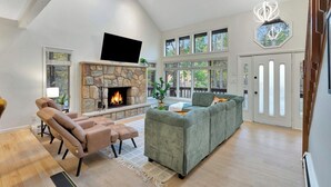 A spacious living room with a stone fireplace, comfortable seating, and large windows. - Unbelievable Poconos Estate - Hot Tub, Game Room (East Stroudsburg)