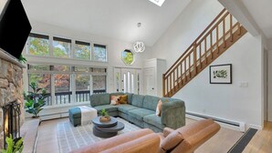 A spacious living room with a sectional sofa, a fireplace, and a staircase. - Unbelievable Poconos Estate - Hot Tub, Game Room (East Stroudsburg)