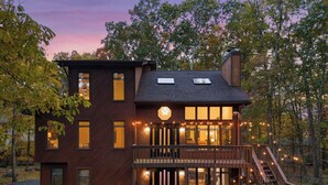 A two-story house with a balcony, a staircase, and string lights. - Unbelievable Poconos Estate - Hot Tub, Game Room (East Stroudsburg)