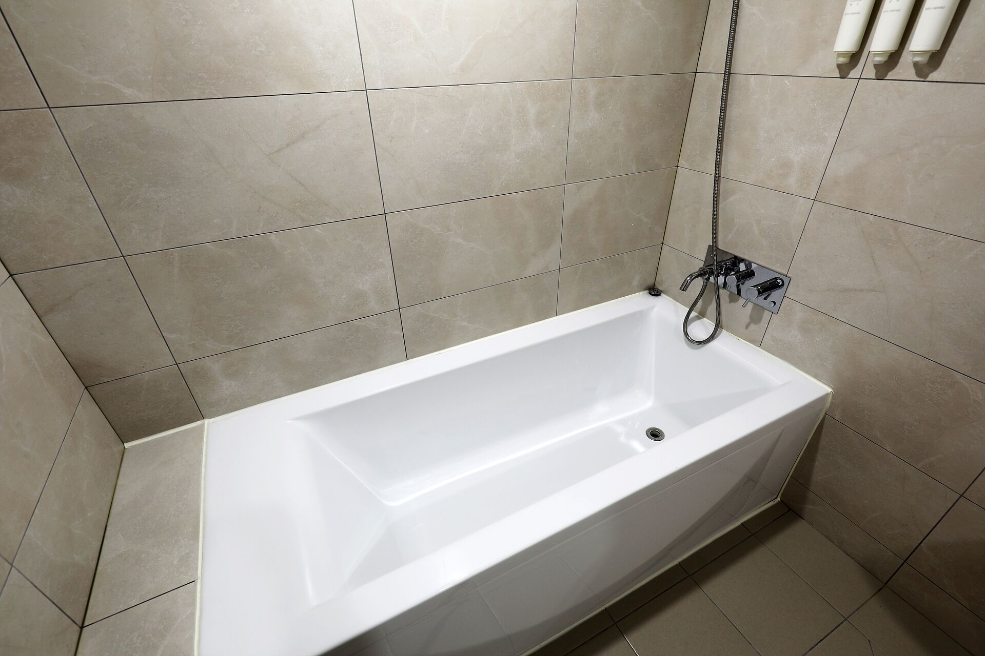 Un baño con una bañera blanca, ducha y grifo empotrado en la pared.