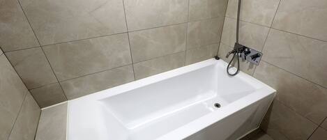 Un baño con una bañera blanca, ducha y grifo empotrado en la pared.