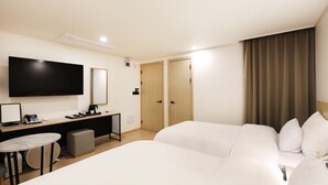Une chambre d’hôtel comprenant un lit, un bureau avec un ordinateur, une chaise, une télévision et une armoire.