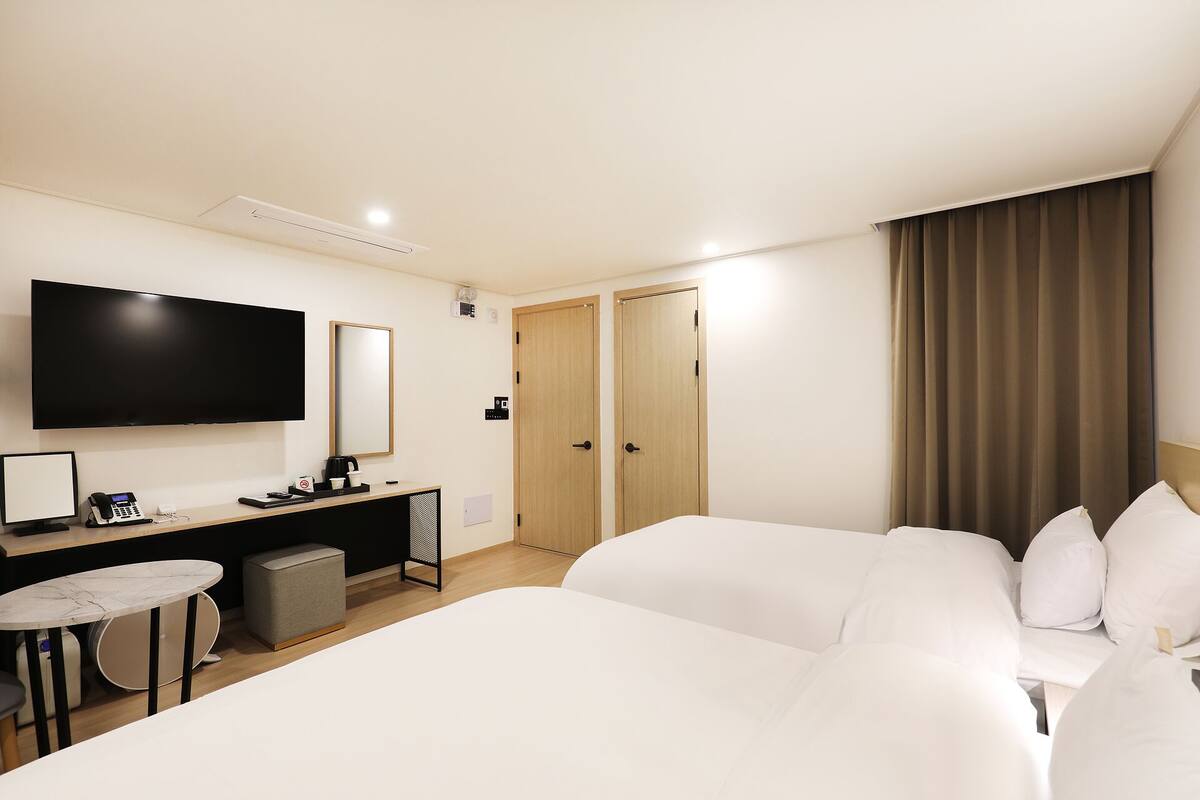 Een hotelkamer met een bed, een bureau met een computer, een stoel, een televisie en een kledingkast.