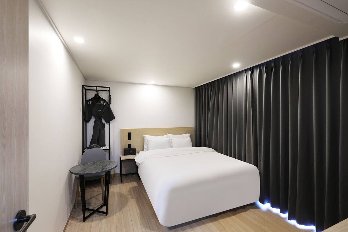 Een moderne hotelkamer met een groot bed, een nachtkastje, een kledingkast en een bijzettafeltje.