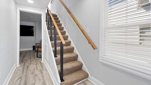 A staircase with carpeted steps, wooden handrail, and black metal balusters. - Cozy 4 Bed 2 Bath Home - Norfolk, Centrally Located (Norfolk)