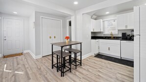 A modern kitchen with white cabinets, a black countertop, and a wooden dining table with two chairs. - Cozy 4 Bed 2 Bath Home - Norfolk, Centrally Located (Norfolk)