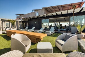 Eine Dachterrasse mit Sitzgelegenheiten im Freien, ein modernes Gebäude und ein klarer Himmel.
