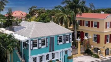 A turquoise building with a red roof, white shutters, and a balcony.
