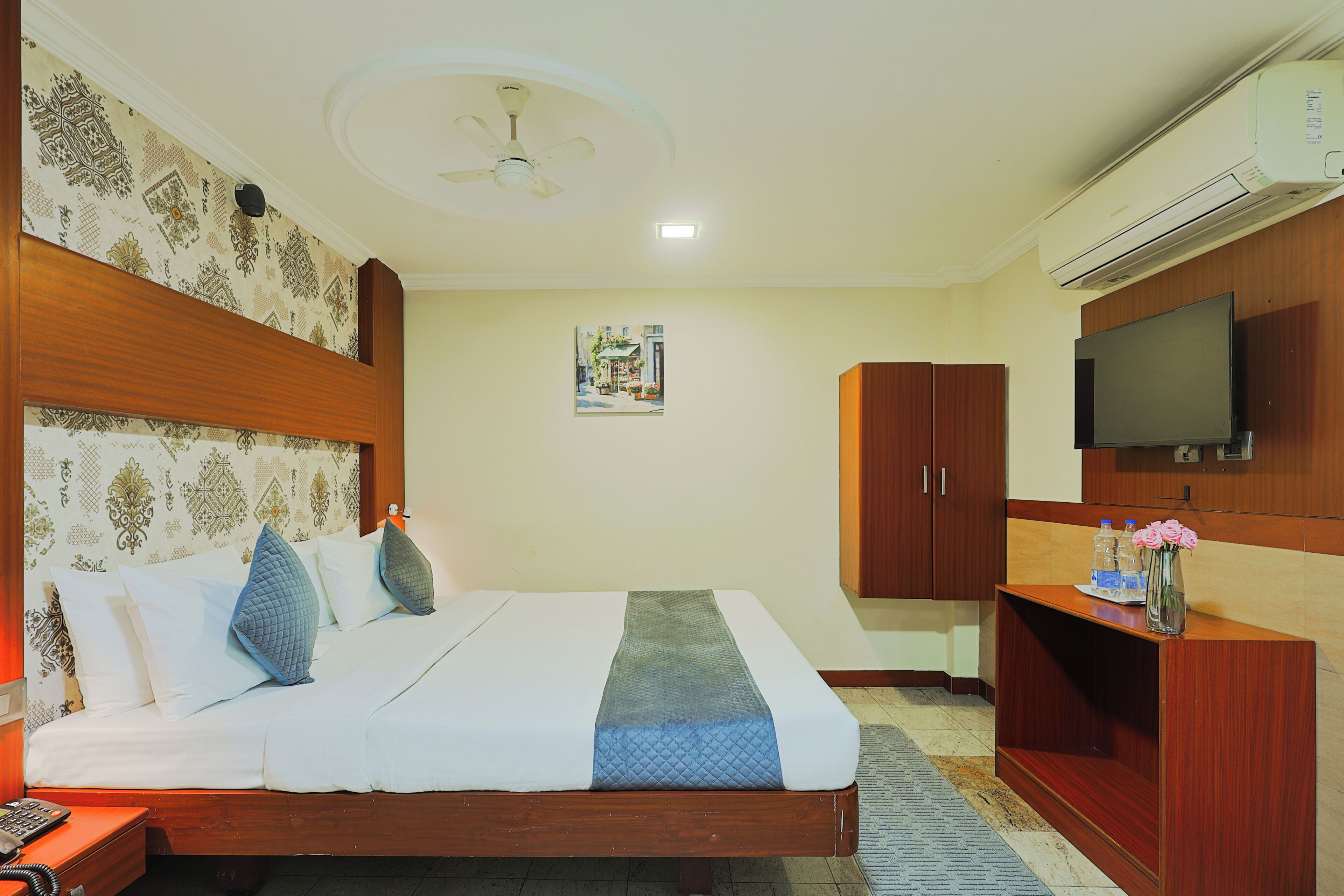 Una habitación de hotel con cama, televisor, armario y aire acondicionado.