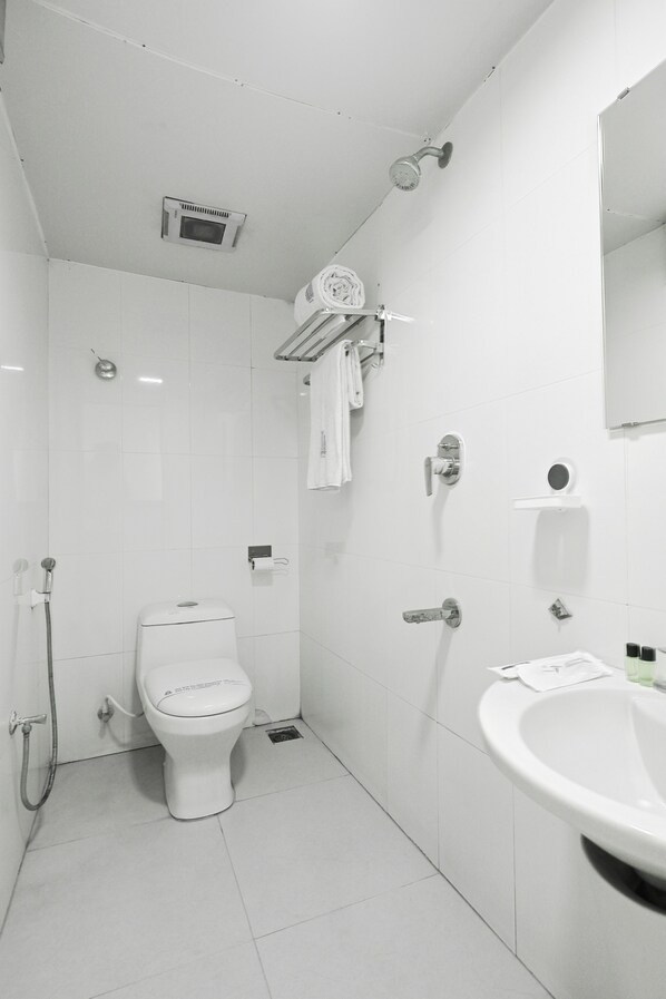 A modern bathroom with a toilet, shower, sink, and a mirror. - Everest Park Residency (Tiruchirappalli)