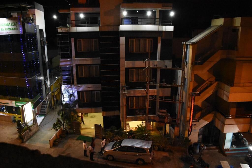 A multi-story building with balconies, a staircase, and a parked car.