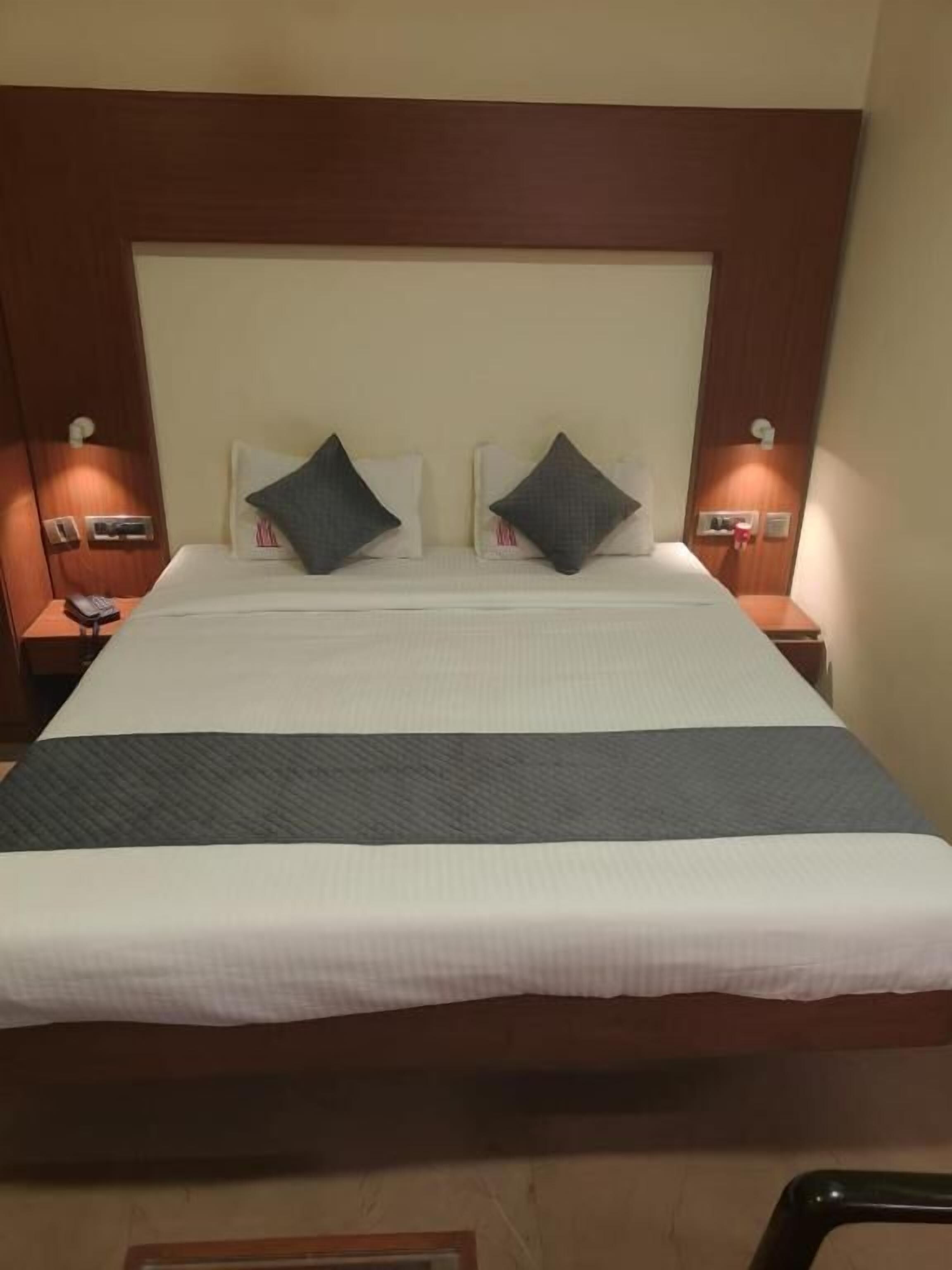 A hotel room with a large bed, two bedside tables with lamps, and a wooden headboard.