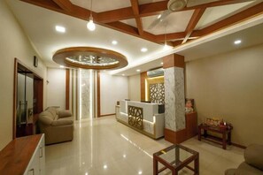 A reception area with a marble reception desk, a sofa, a glass coffee table, and a ceiling fan. - Everest Park Residency (Tiruchirappalli)