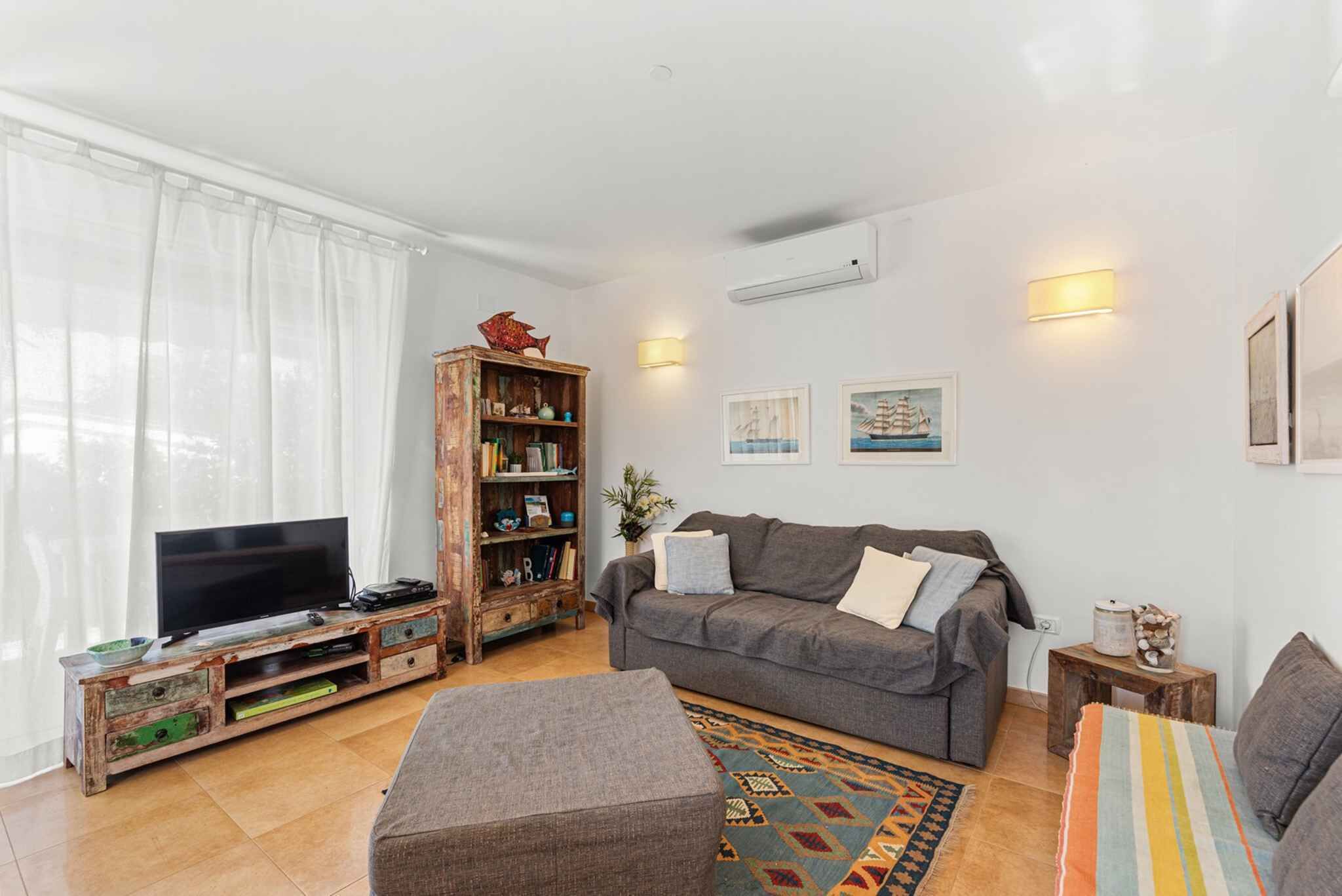 A living room with a TV, sofa, and wooden bookshelf.