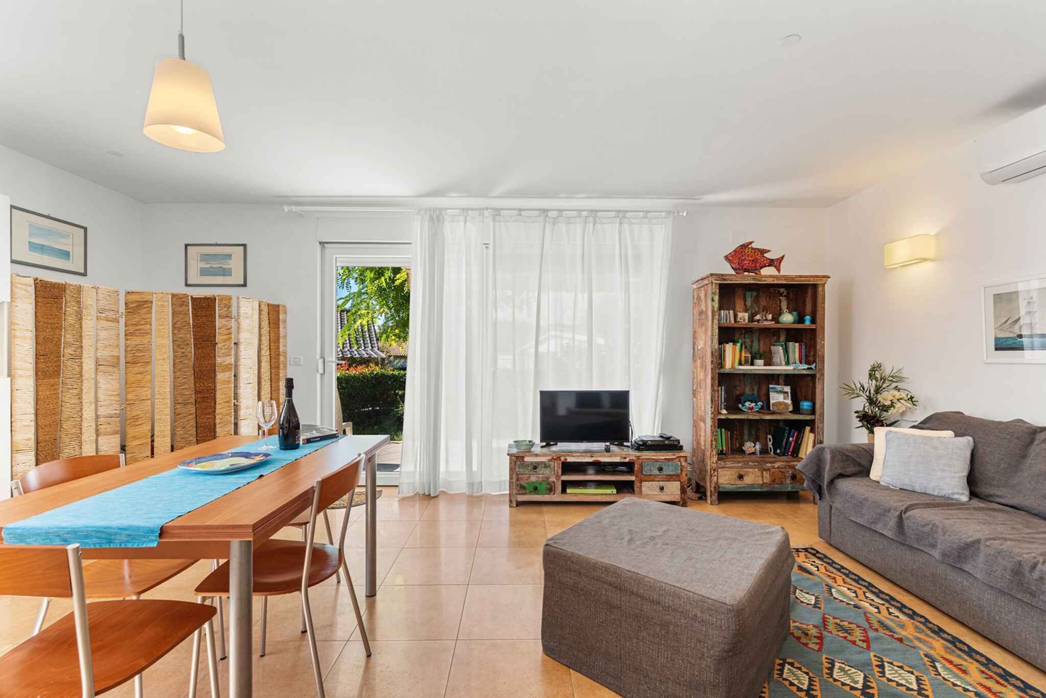 A modern living room with a dining area, a television, a bookshelf, and a sofa.