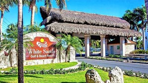 Cartell de resort amb un logotip, una construcció amb teules de palla i palmeres.